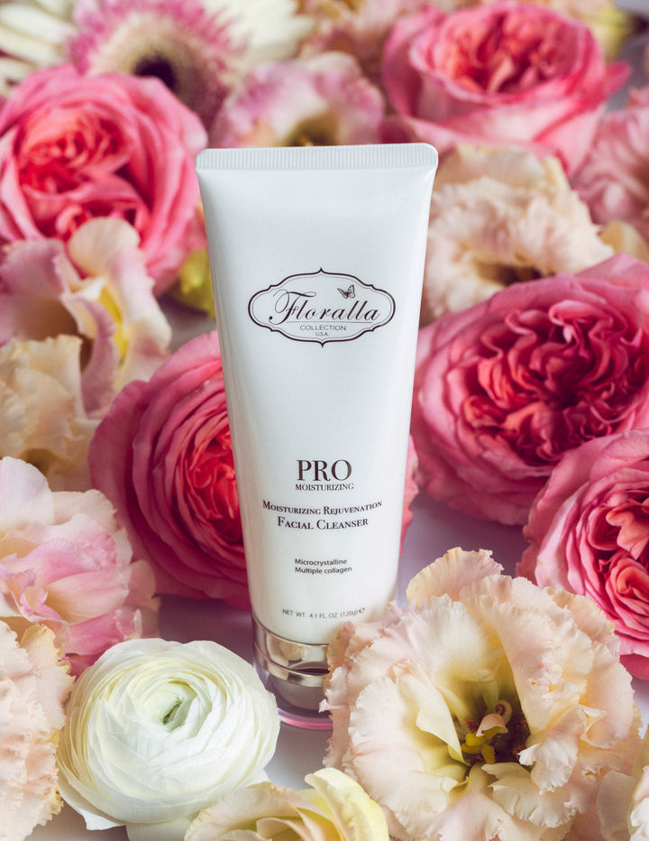 Floralla Pro Moisturizing Rejuvenating Facial Cleanser, in white tube with pink floral accents, surrounded by pink and white roses.